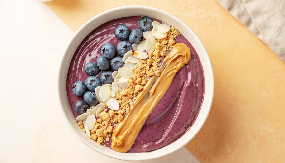 Blueberry protein smoothie bowl topped with blueberries, almonds, and graham crackers