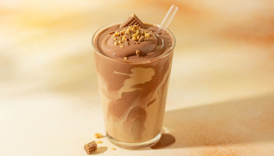 Chocolate peanut butter protein smoothie in a glass with a straw