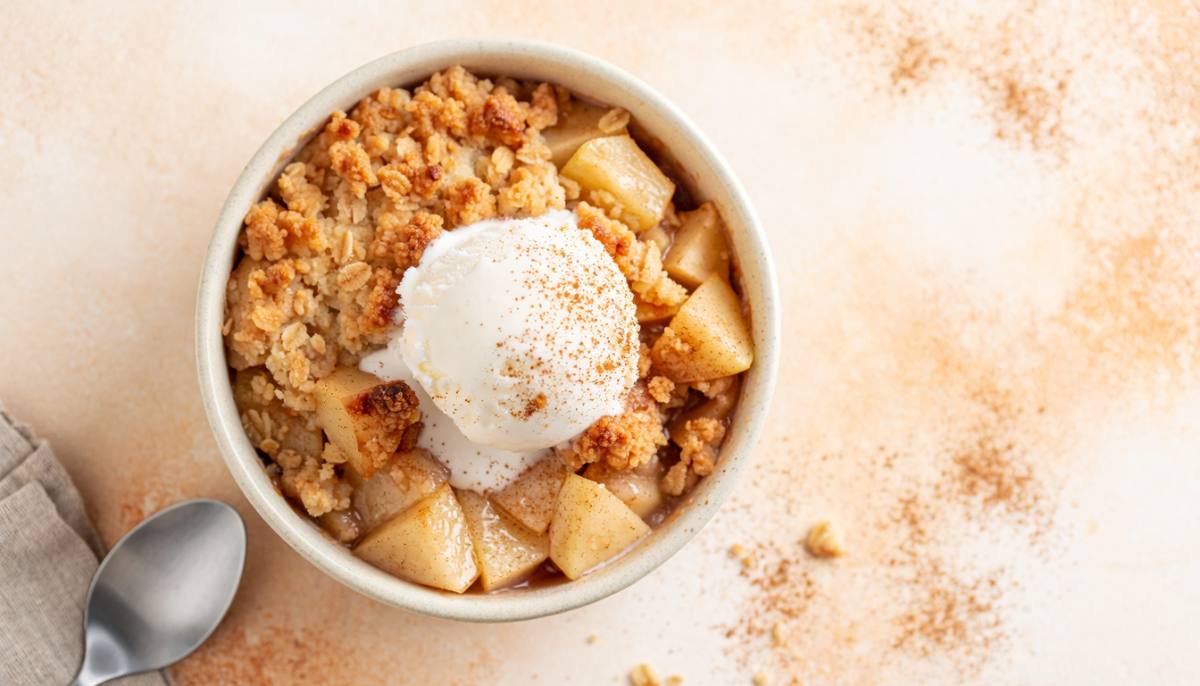Single-serve apple crumble with oat topping and a scoop of vanilla ice cream