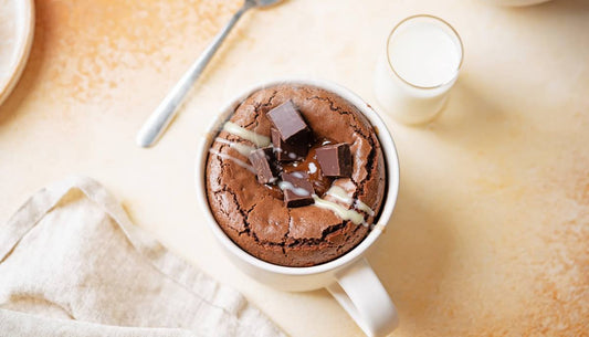Overhead of a chocolate protein brownie mug cake with chocolate chunks and cream drizzle