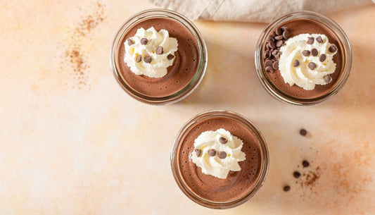 Chocolate protein mousse in glass jars with whipped cream and chocolate chips
