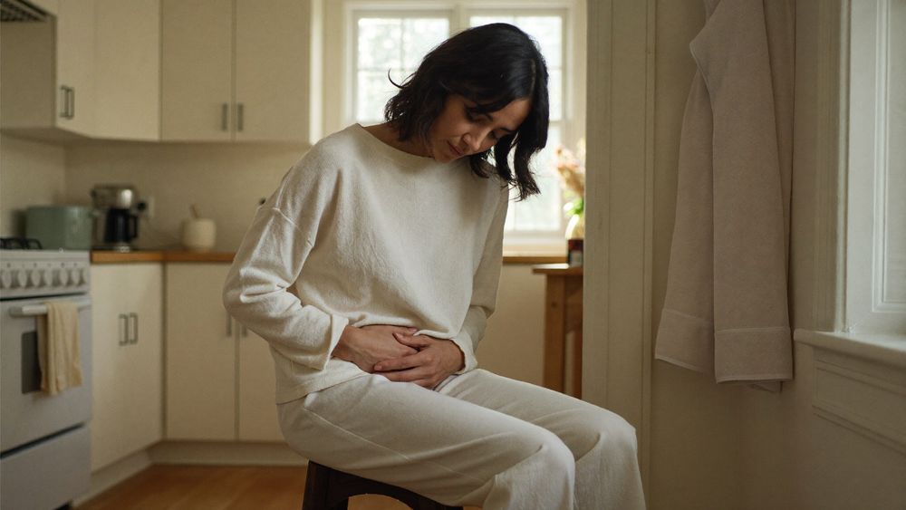 A woman resting her hands on her midsection in a kitchen